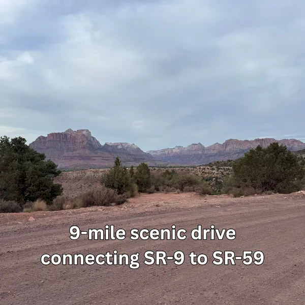 An image of a dirt road in a desert landscape leading toward red mountains under a cloudy sky, with on-screen text: "9-mile scenic drive connecting SR-9 to SR-59.”