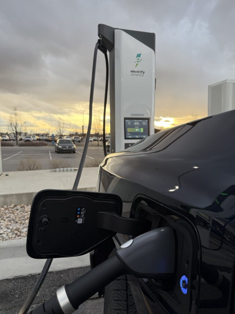 Close up image of a car plugged in at an Electrify America charging station at sunset in Spanish Fork, UT.